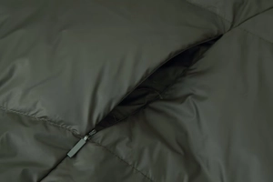 Detail view of the durable zipper and quilted stitching on dark olive hooded cotton coat