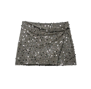 Detailed close-up of grey sequin mini skirt with side wrap tie and silver glitter