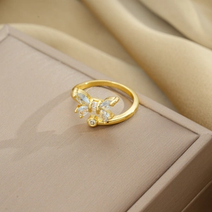 Close-up of golden butterfly ring with zircons resting on a beige velvet jewelry box