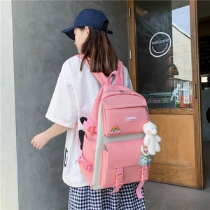 Side view of a pink and beige color-block school backpack with a cute bear plush pendant