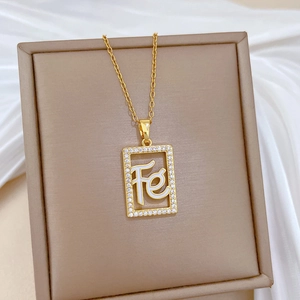 Detail of gold rectangular pendant with pavé diamonds and Fe letter on satin