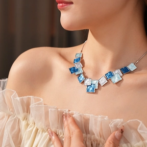 Close-up of geometric blue enamel square pendant necklace worn by a female model