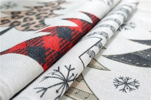 Macro shot of linen-blend fabric texture with leopard trees and red plaid snowflakes