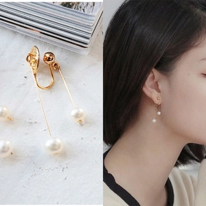 Detail view of long freshwater pearl clip-on earrings with gold mosquito coil clasps