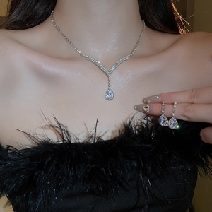 Elegant silver V-shaped necklace and teardrop rhinestone earring set on a female model