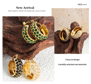 Detailed view of C-shaped earrings with sparkling green, black, and white rhinestones