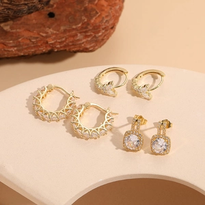 Detailed view of three pairs of gold-plated zircon earrings on a curved display stand