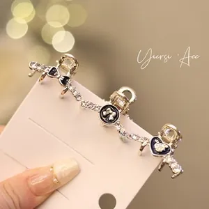 Detail of three mini rhinestone bow hair clips with black enamel on a display card