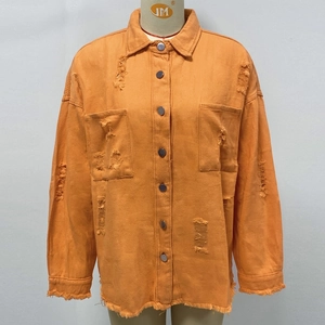 Detail of orange distressed denim jacket with frayed hems and ripped texture