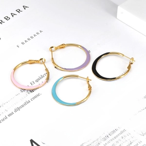 Detail of colorful enamel hoop earrings in pink, purple, blue, and black on a book