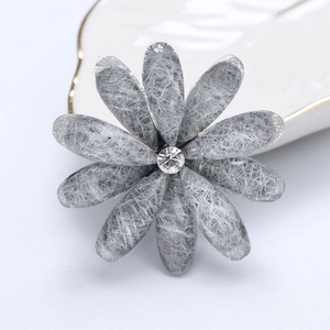 Detailed macro of silver flower brooch with wire mesh texture and center rhinestone