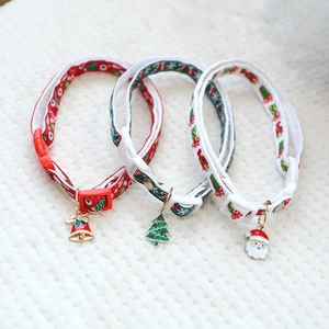 Three-piece Christmas pet collar set with bells and festive charms on white knit background