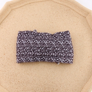 Detailed close-up of dark brown printed floral baby headband with soft pleated texture