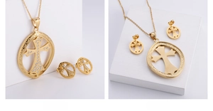 Detail of gold plated necklace and earrings set with white rhinestones and cross motif