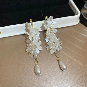 Macro detail of elegant floral tassel earrings with pearl drops on white jewelry box