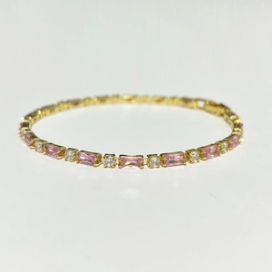 Detailansicht eines vergoldeten Armbands mit glänzenden rosa Zirkonia-Edelsteinen