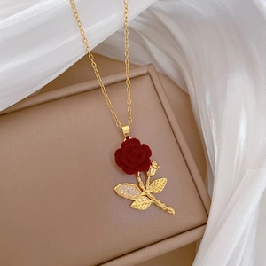 Macro shot of red velvet rose pendant with crystal-set golden leaves on titanium chain