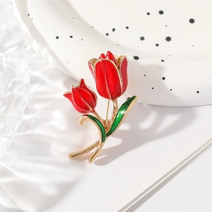 Elegant red enamel tulip brooch with golden metal leaves on a decorative white plate