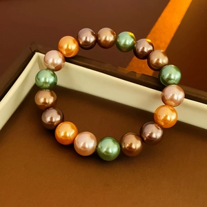Vue rapprochée d'un bracelet de perles colorées métallisées dans un écrin de luxe