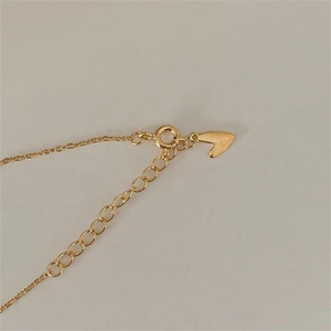 Detail of gold LOVE necklace with heart pendant, clasp, and extender chain links