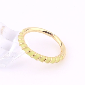 Close-up of golden adjustable ring featuring yellow enamel inlay and diagonal texture