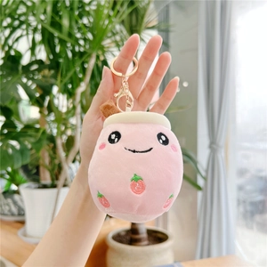 Close-up of pink plush milk tea keychain with strawberry embroidery and golden ring