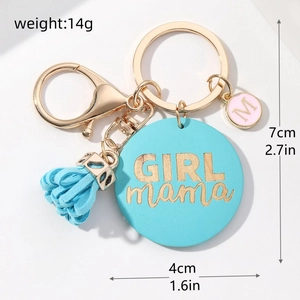 Detailed macro view of GIRL mama keychain with blue tassel and gold metal hardware