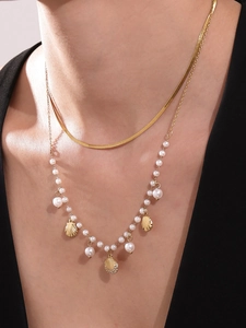 Close-up of double-layered gold stainless steel necklace with pearl shell pendant on model