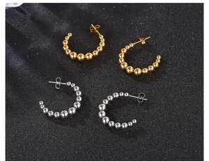 Detailed view of gold and silver C-shaped beaded earrings on a black background