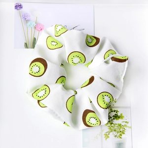 Detail of a white elastic scrunchie with green kiwi fruit print on soft fabric texture