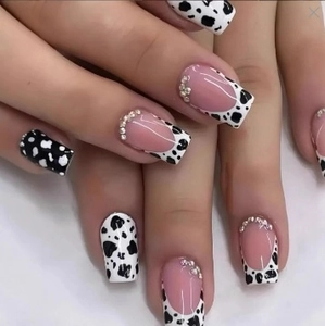 Detail of long square press-on nails with black and white cow print and rhinestone edges