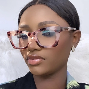 Close-up of tortoise shell square frame glasses worn by a model on a soft plush backdrop