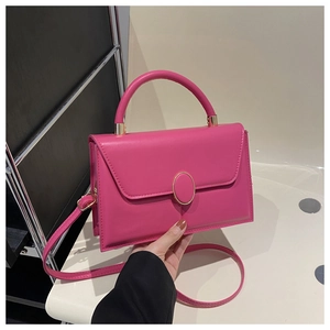 Détail du sac bandoulière rose fuchsia avec boucle dorée et finition brillante