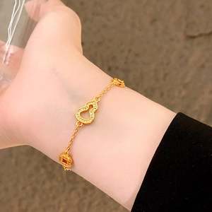 Détail du bracelet doré avec pendentif calebasse évidé et breloques pièces au poignet