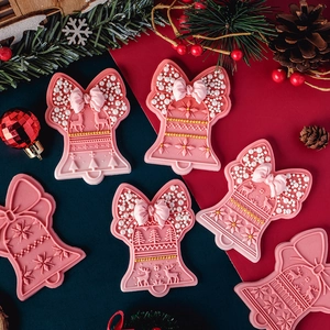 Pink Christmas bell cookie mold set with snowflake and bow patterns on festive background