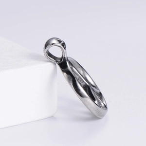 Close-up of brushed silver peace sign pendant on minimalist white geometric block