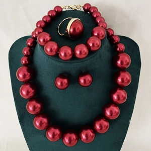 Detailed set of red faux pearl jewelry with gold metal accents on green velvet display