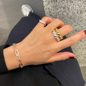 Close-up of 925 sterling silver twisted rope ring and geometric chain bracelet on hand
