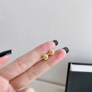 Detailed close-up of lemon yellow enamel stud earrings held between fingers for size reference