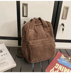 Detail eines braunen Cord-Rucksacks mit Tragegriffen oben und Reißverschluss-Fronttasche