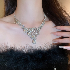 Close-up of elegant silver teardrop pendant necklace worn by a model in soft lighting