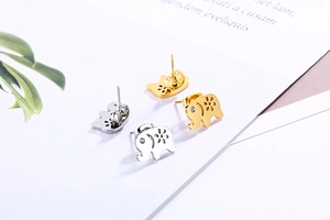 Macro shot of gold and silver elephant stud earrings with hollow floral and crystal details
