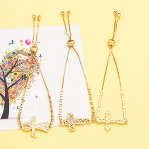 Detail of adjustable gold cross bracelets with ankh charms and white zircon pavé