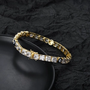 Bracciale tennis dorato con zirconi quadrati e ciondoli occhio blu su sfondo nero
