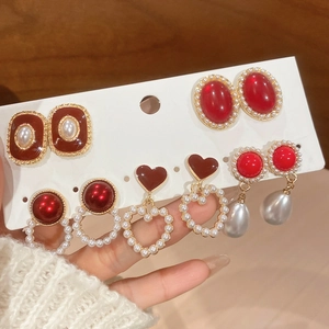Detailed view of vintage gold-tone earrings set with red resin and pearls on a display card