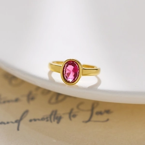 Detail of a vintage gold stainless steel ring with an oval pink diamond on a white plate