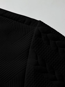 Close-up of black heavy-duty knit fabric showing intricate textured stitching and patterns