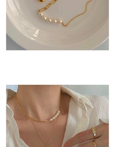 Detail view of gold chain and pearl splicing necklace on a white plate and model