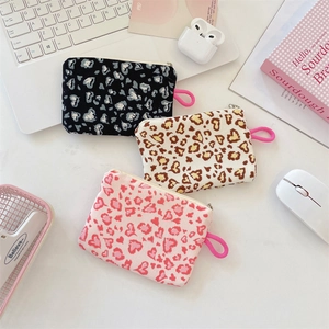 Three heart leopard print coin purses in black, beige, and pink colors on white desk