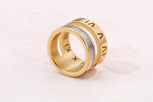 Macro shot of gold wide band ring with Roman numerals and white shell inlay detail